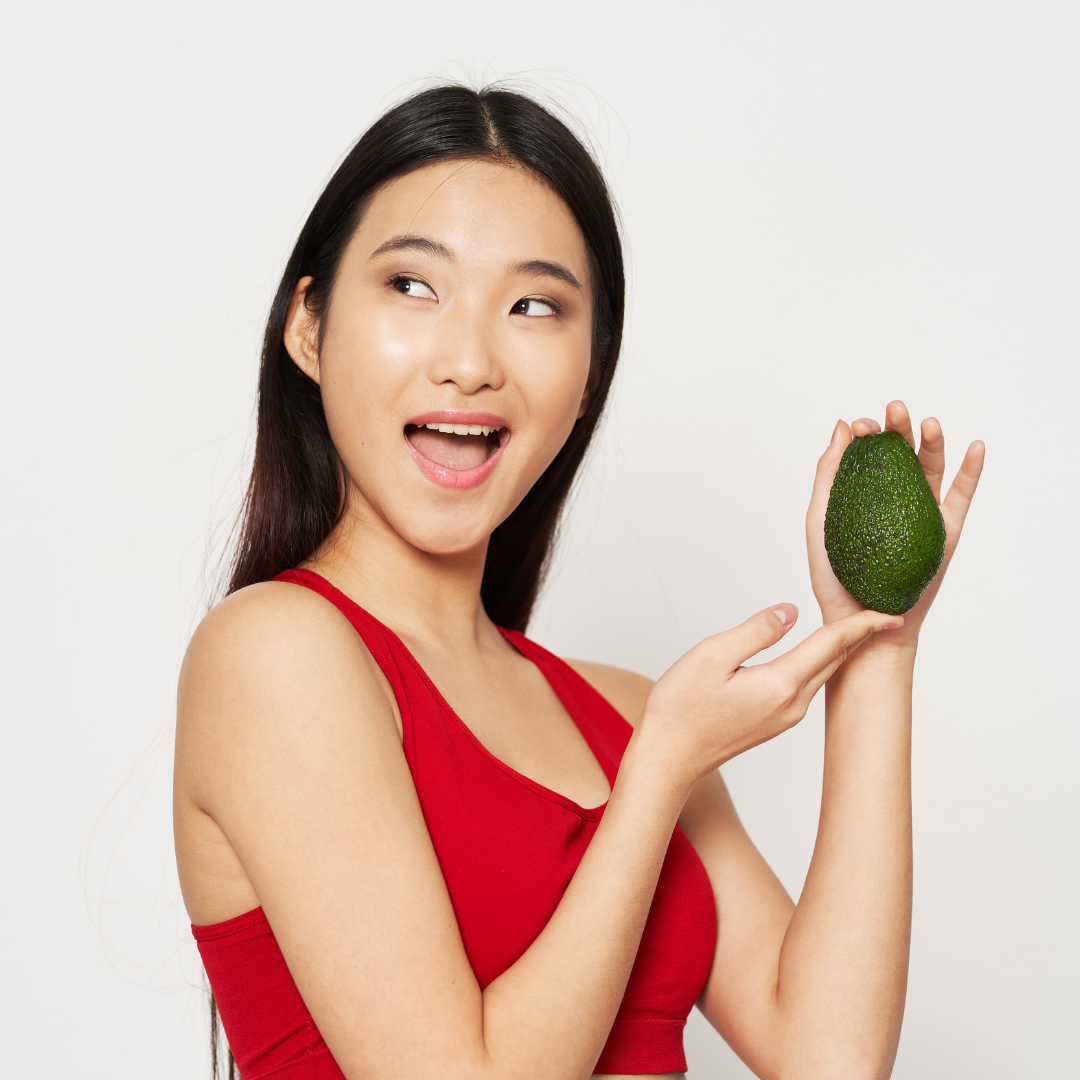 Woman holding an avocado discovering the power of superfoods for her skin.
