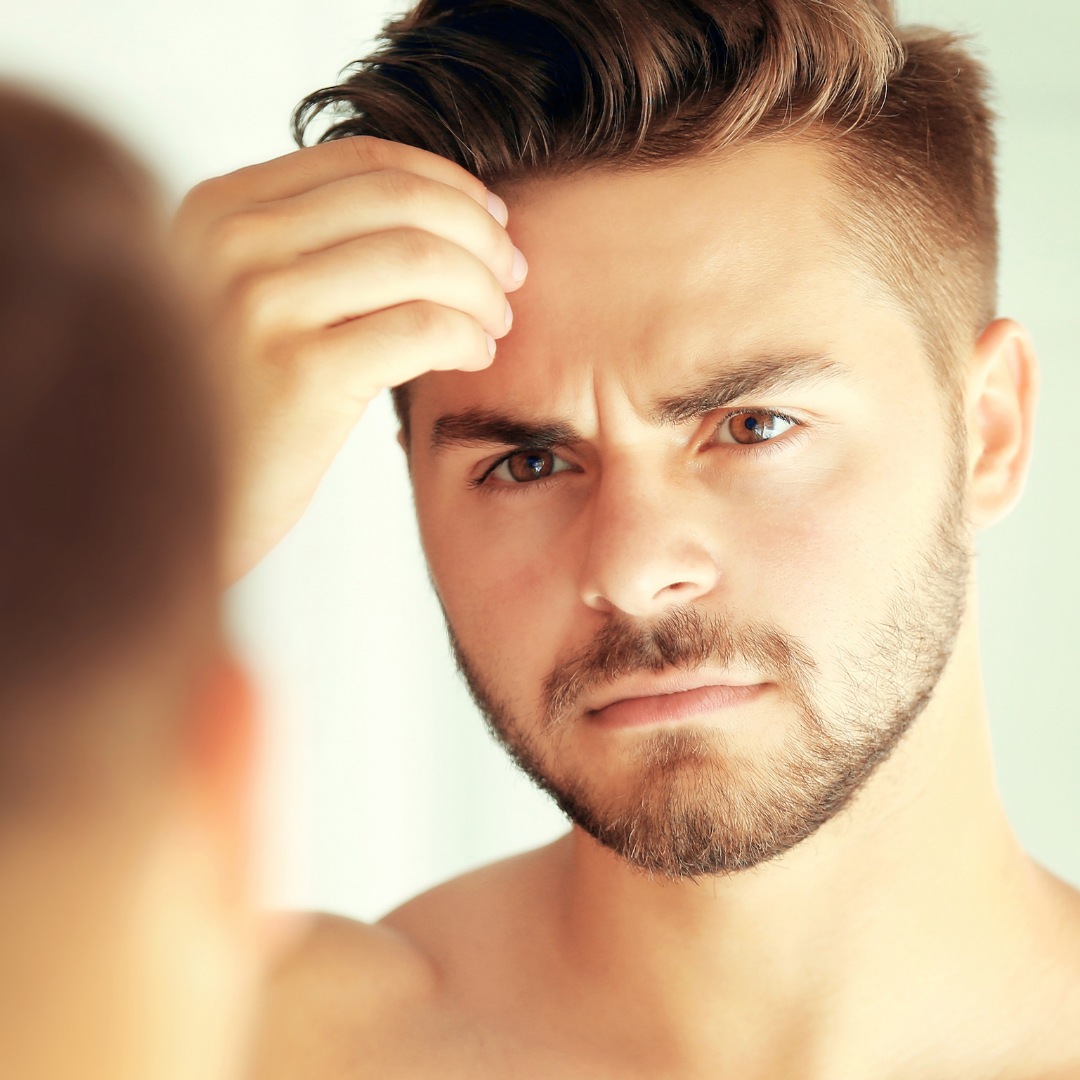 Man considering aesthetics for men as he looks in the mirror